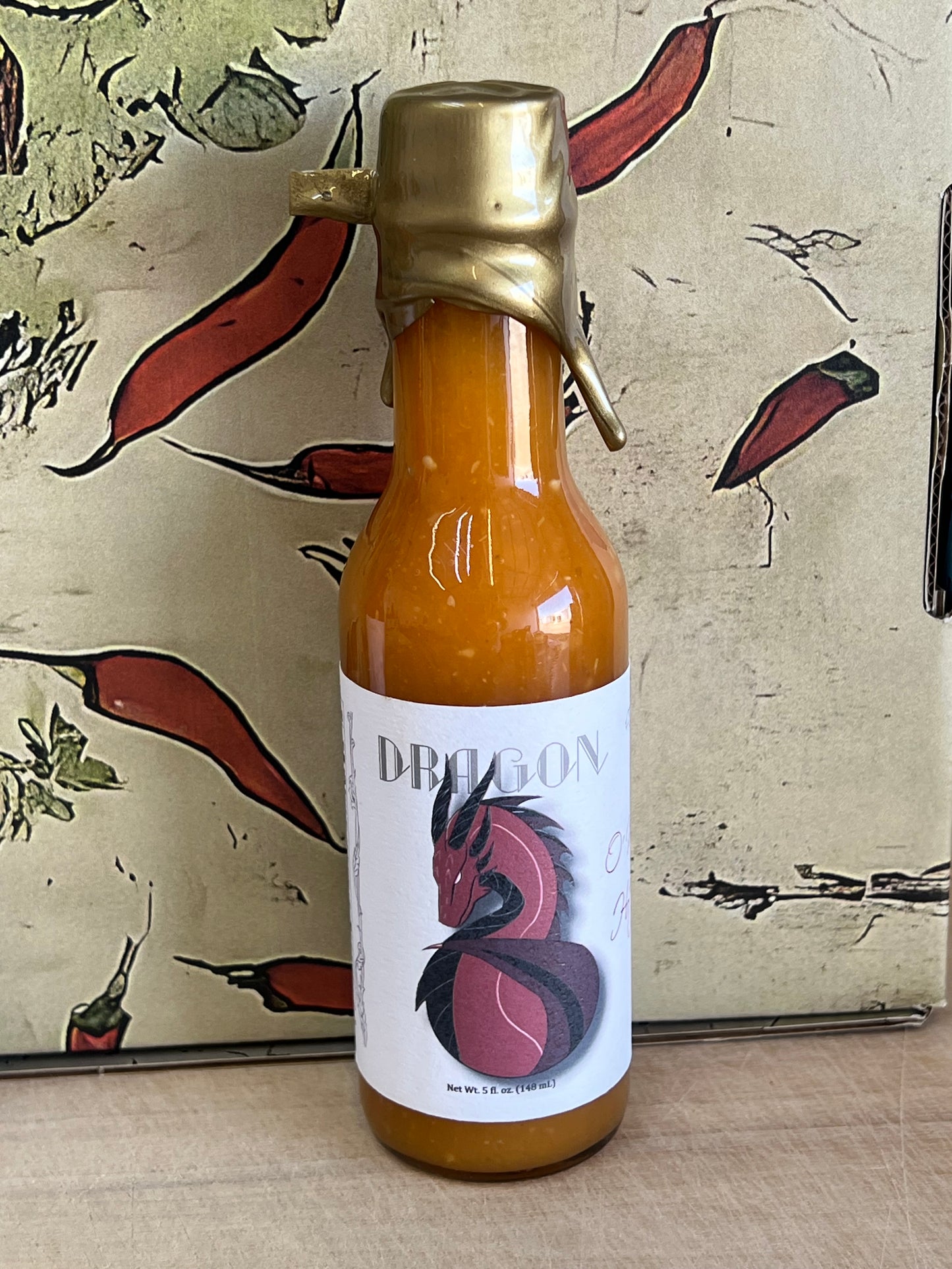 Bottle of Orange Habanero Sauce surrounded by fresh habanero peppers and orange slices